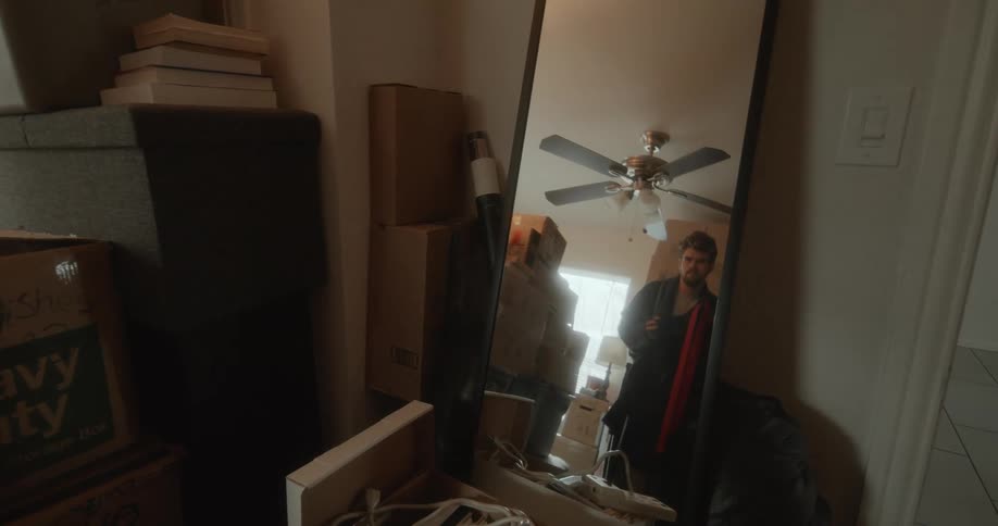 Mirror in storage room reflects man holding jacket up against himself