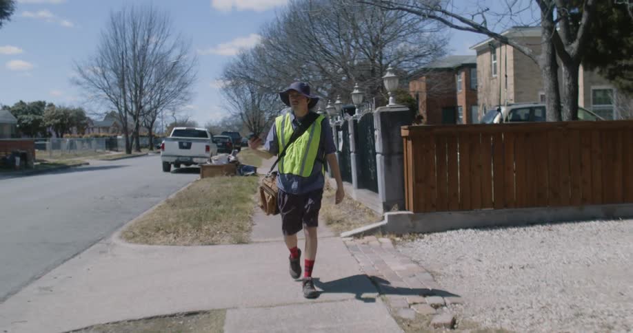 A worker is walking outside on the sidewalk in the middle of the day