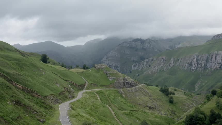 An empty mountain road winding and curving around the slopes of the Cantabrian mountain range