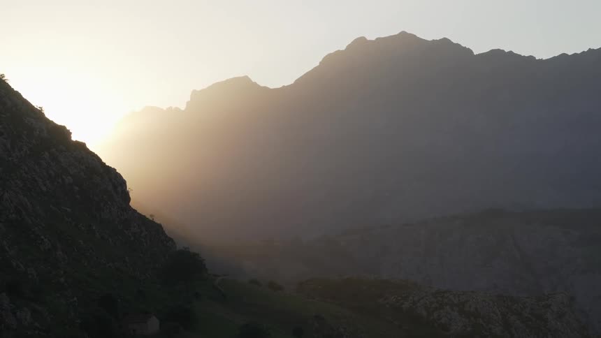 Sunlight shines through the haze over the jagged peaks of the Cantabrian mountain range