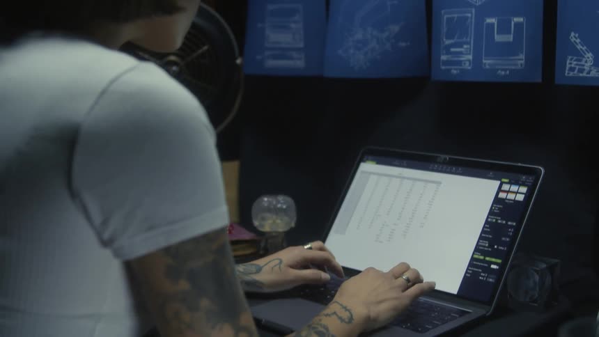 A young asian woman is working on a spreadsheet on her laptop inside of a warehouse