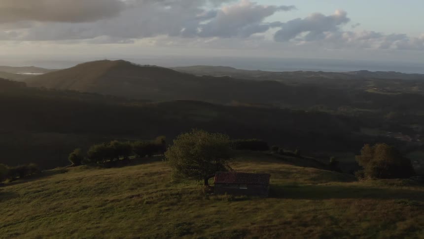 The lush green landscape of Northern Spain with golden sun rays on the horizon