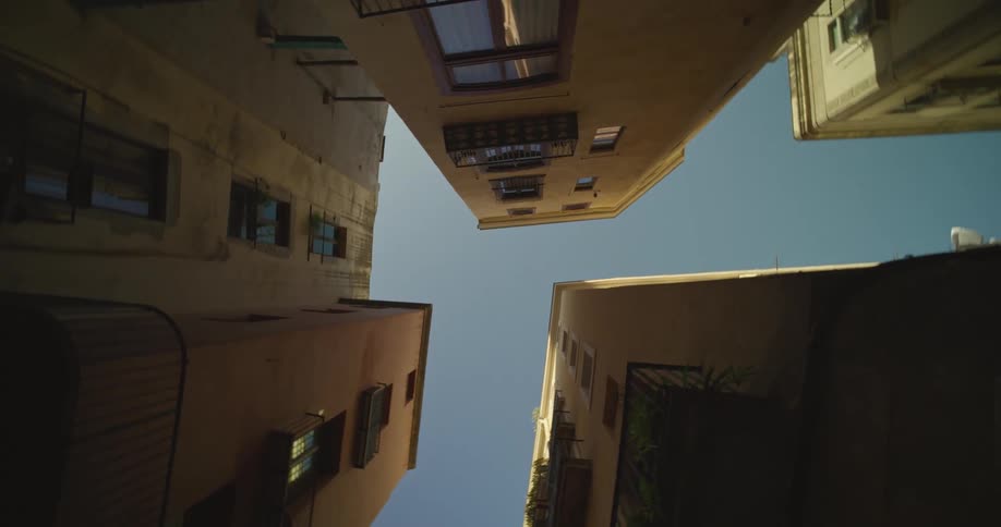 Looking up at tall, narrow buildings in a city