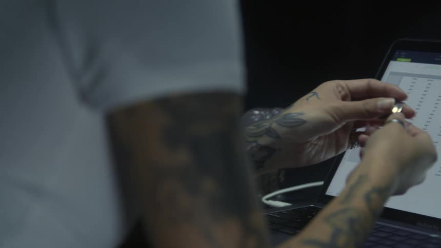 Young tattooed woman stops typing on a laptop to pick up a spinning top