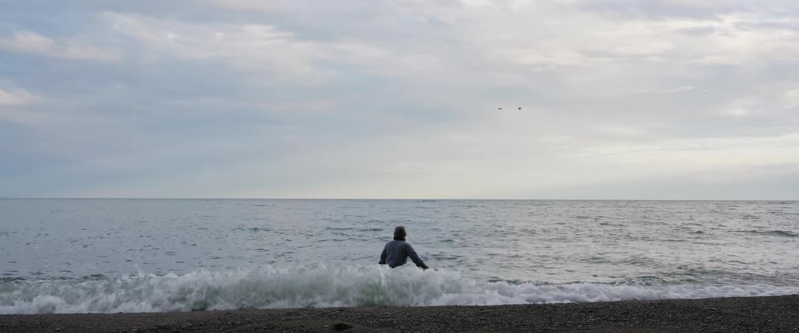 Man with shirt and pants walks into sea