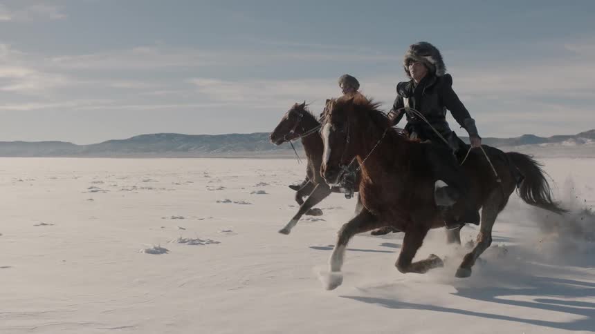 People race their horses across a snow covered field