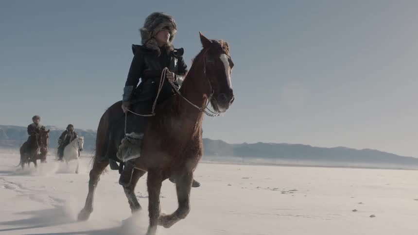 Men riding horses in slow motion in the snow