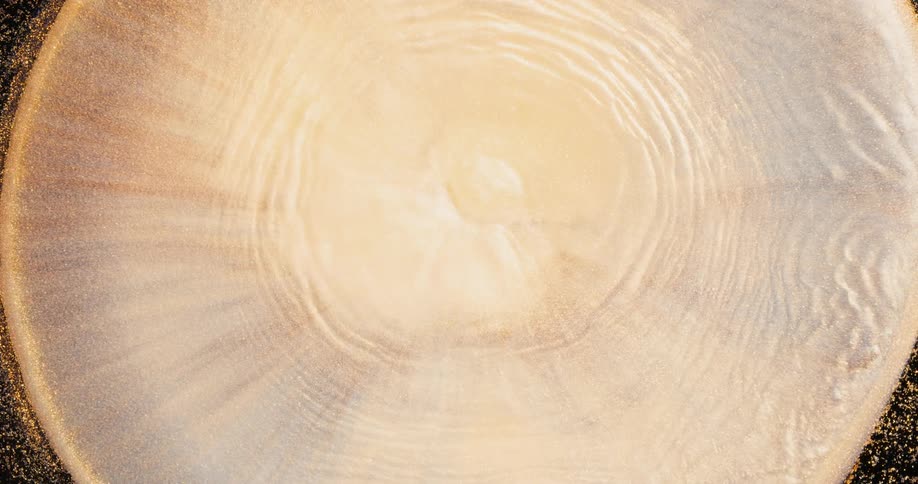 Pale glowing center expands in concentric rings against dark mixture