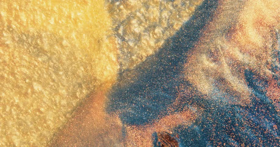 A yellow texture moves on a blue and yellow surface as a blue and orange glittery area moves over and covers that texture