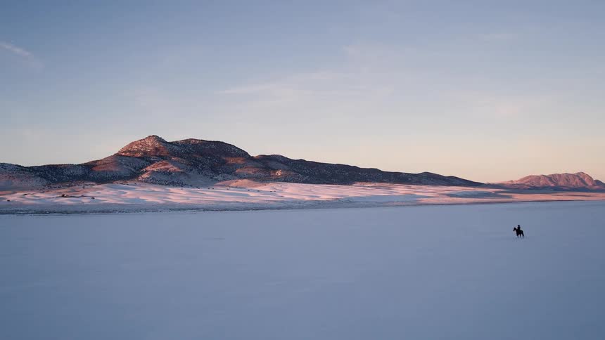 Someone riding a horse across a snow-covered field