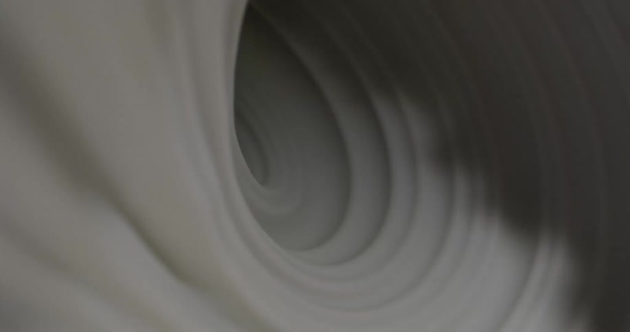 Shadows gather and flow over a white surface of concentric circles