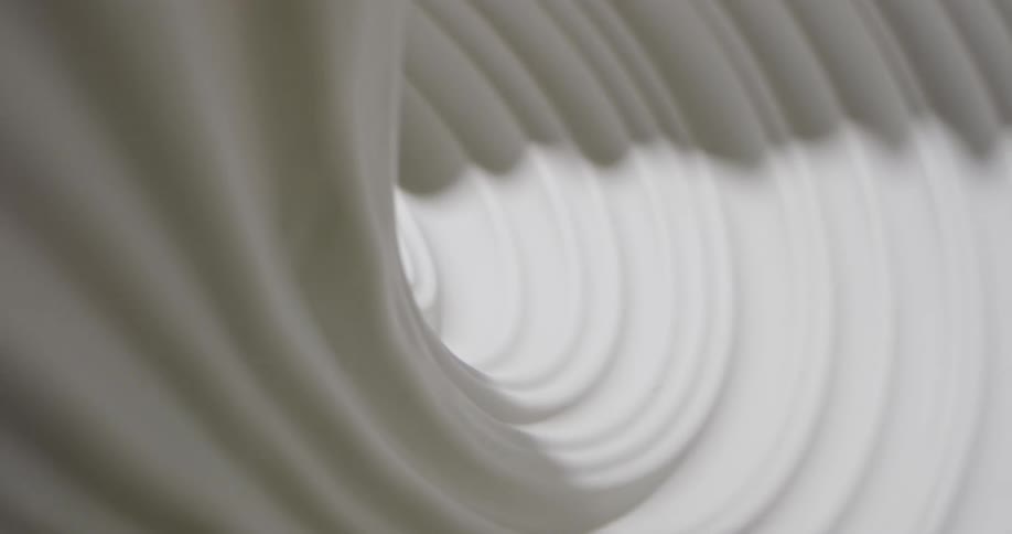 Light shines on a white swirling substance as it spins into a tunnel and becomes dark as the shadows move and grow