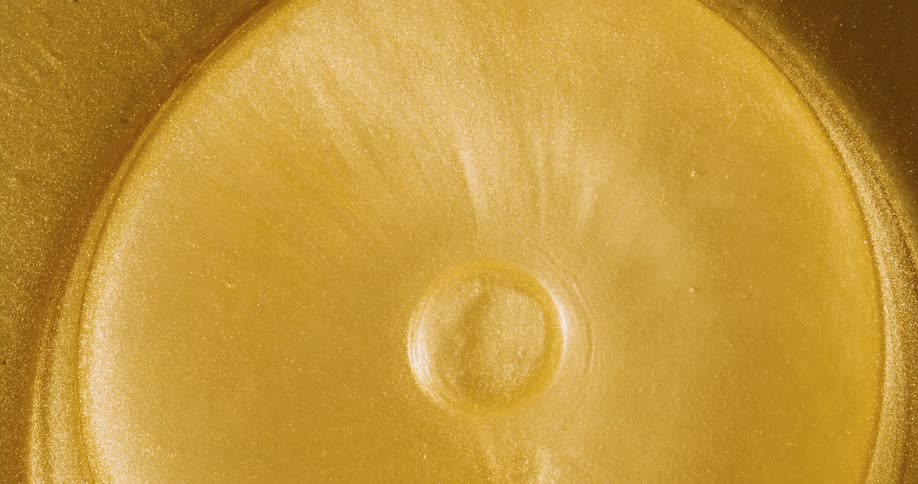 Light shines on an orange substance as it ripples and circles move outward as it grows