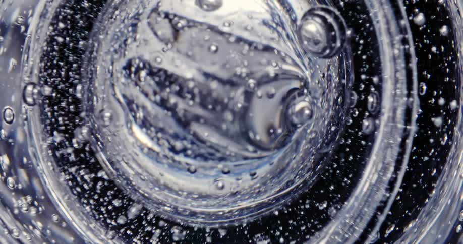 Bubbles rise from a liquid that is rippling and moving