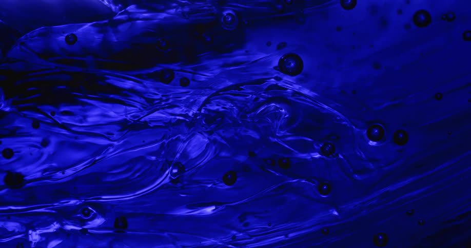 Dark circular shapes are gliding along with the motion of the blue organic liquid as it moves