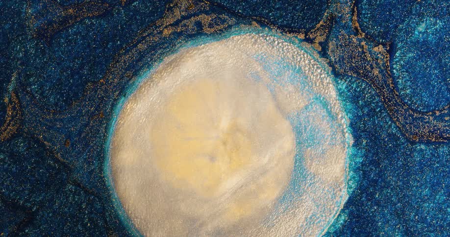 A water droplet expands as it falls in a shimmery liquid