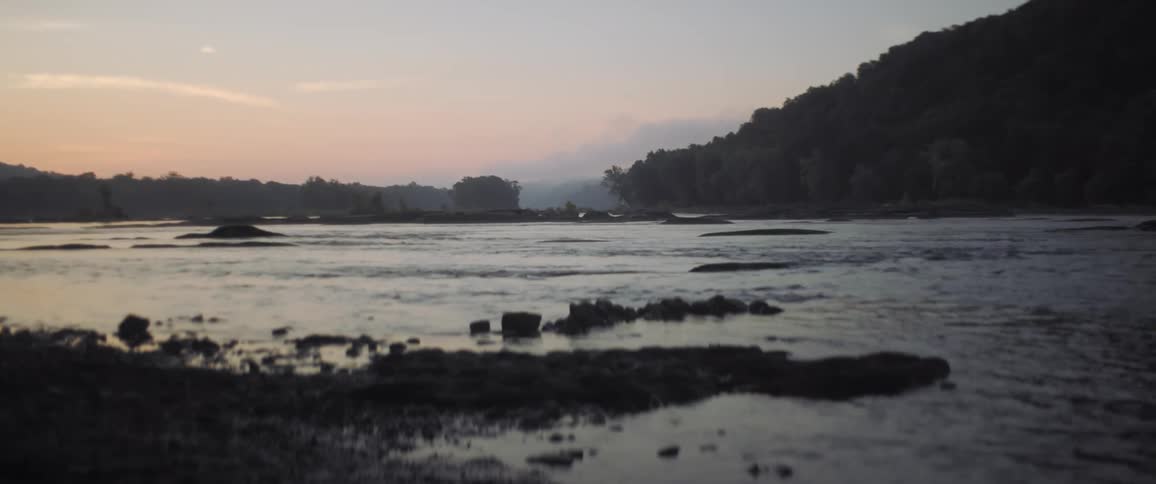 Ripples and gentle waves lapping at the rocky shore at sunrise