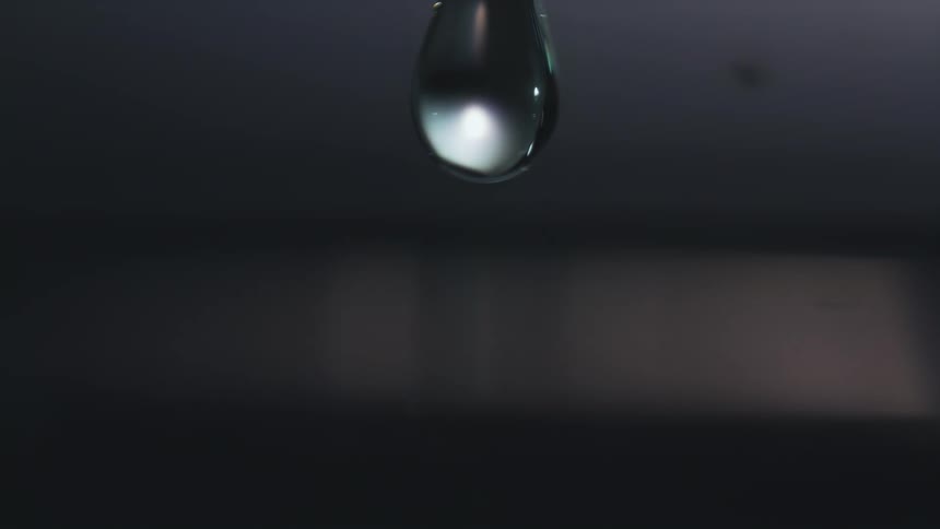 Light shines on a water droplet as it falls into the water below