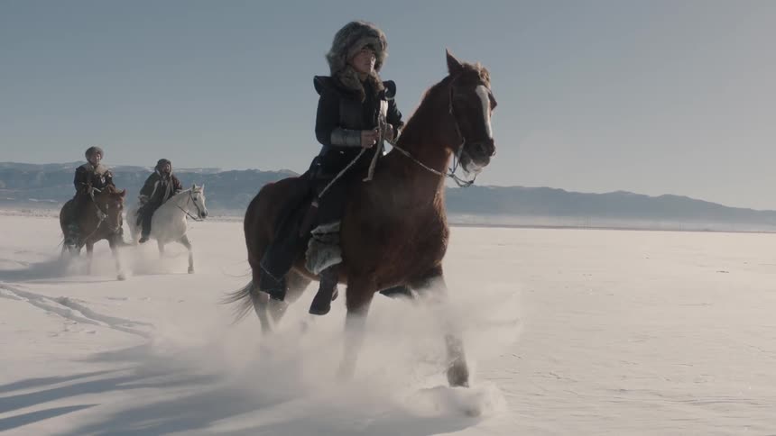 People riding horses across a snow covered pasture