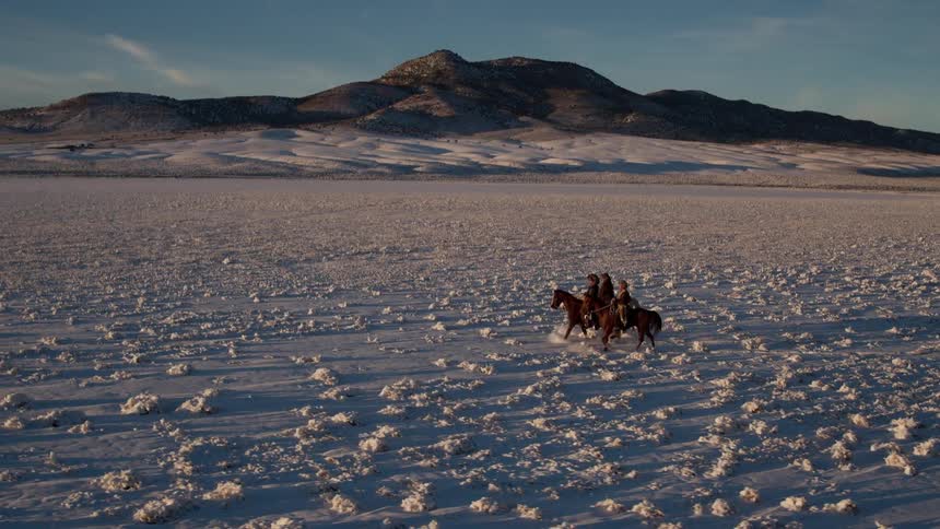 Men riding horses across a snow-covered landscape