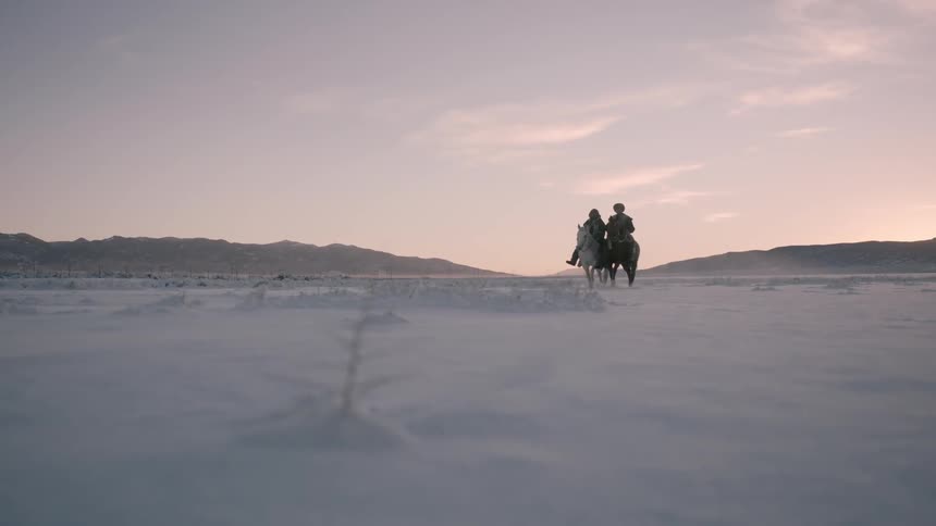Men riding horses in slow motion in the snow