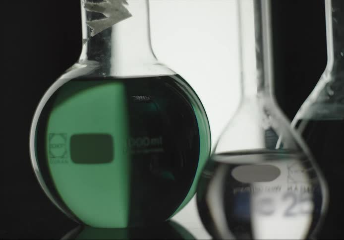 Light turns on to shine through glass containers holding clear and green fluids