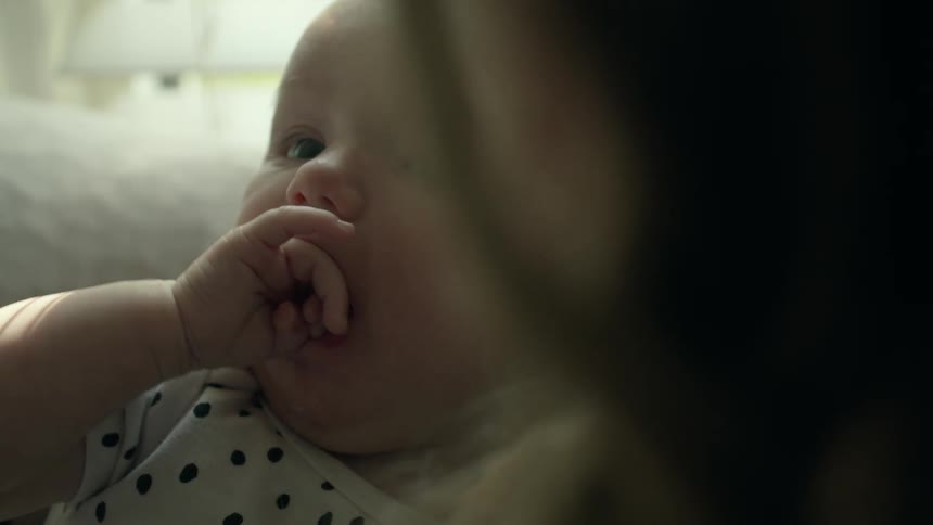 Mother with wavy hair holds and looks down at newborn baby