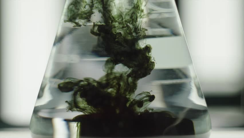 Close up of green liquid being poured into glass beaker