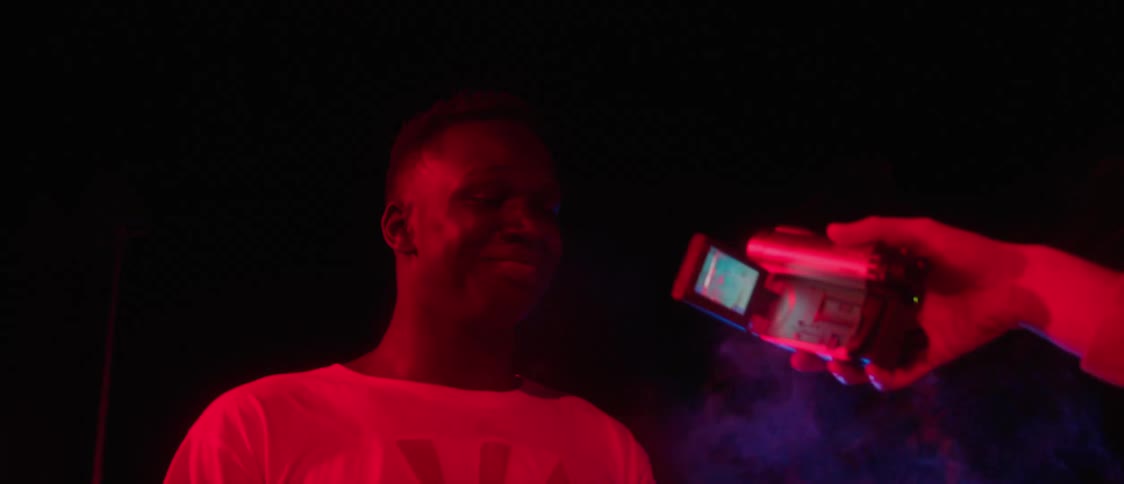 Person films man with white t shirt smoking in red light at night