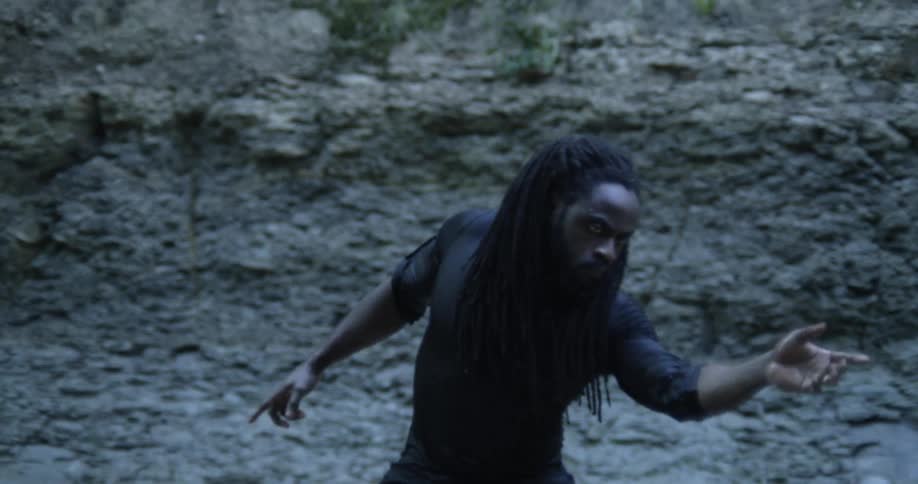 A man dancing in front of a rock wall
