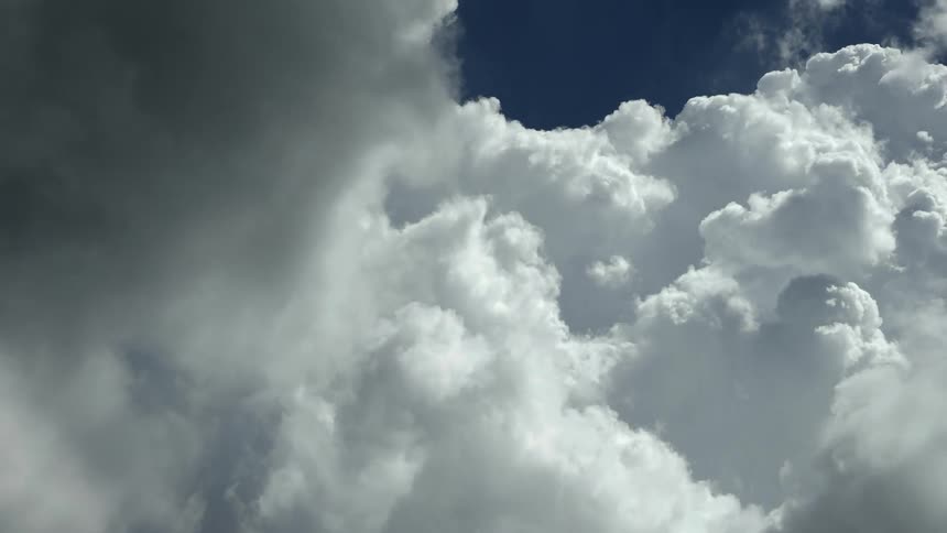 Time lapse of dark storm clouds moving over white clouds on a deep blue sky