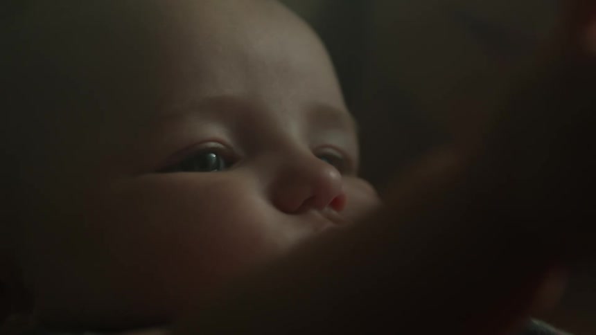 A baby is laying down looking around and moving their hands