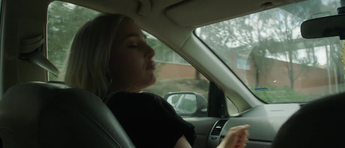 Young girl driving a car through town dancing and singing with the passenger