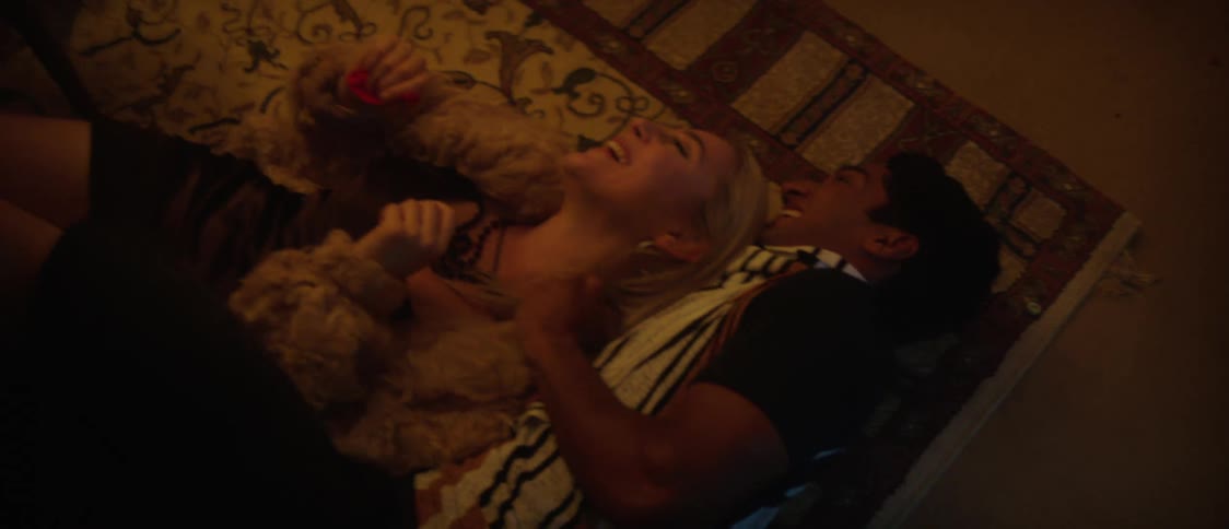 Two young happy friends laugh laying over a carpet in the living room after a crazy party