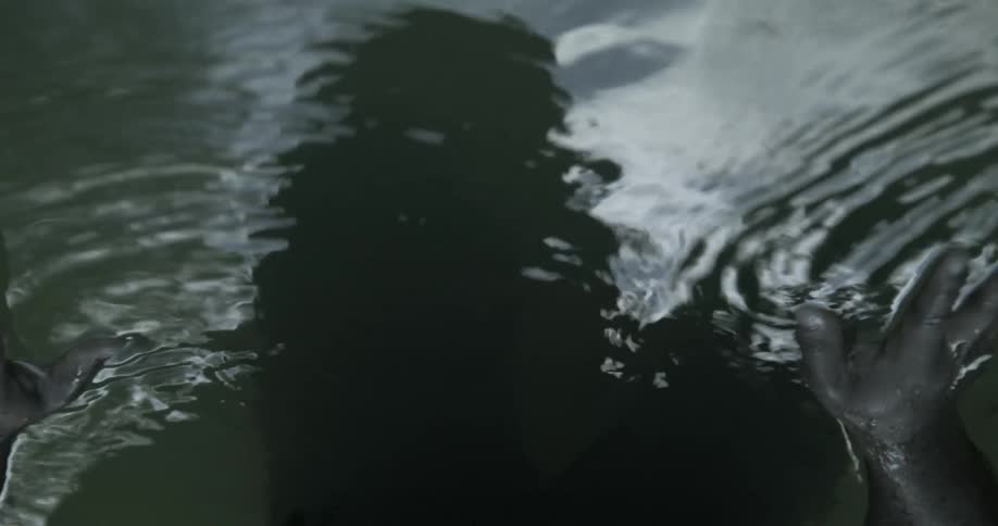 A person is looking down into the water and moving their hands through it