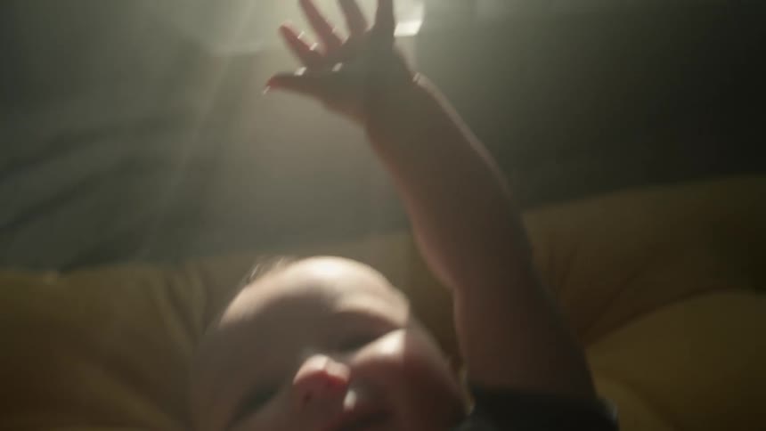 A baby is laying on some cushions in a sunny room