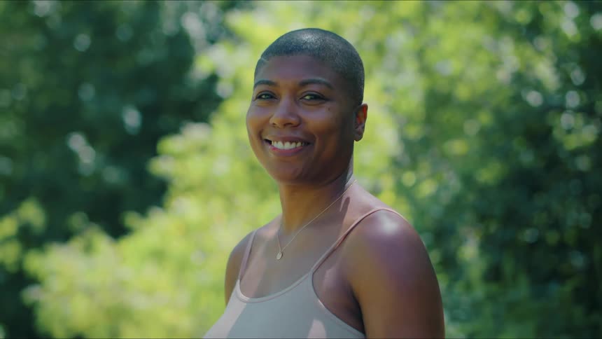 Woman standing outdoors turns and smiles