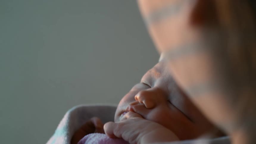Blonde mother holds newborn baby sleeping
