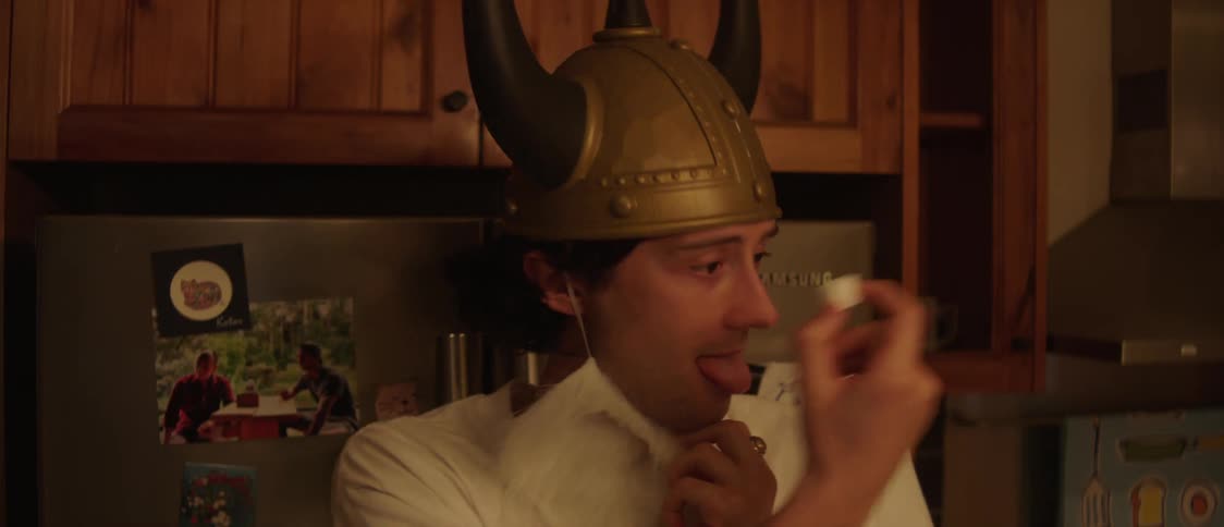 Man lowers fake costume beard to eat while he stands in kitchen talking