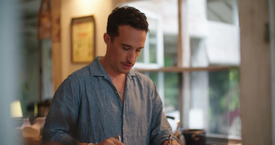 Man smiles while standing at kitchen counter tossing a salad