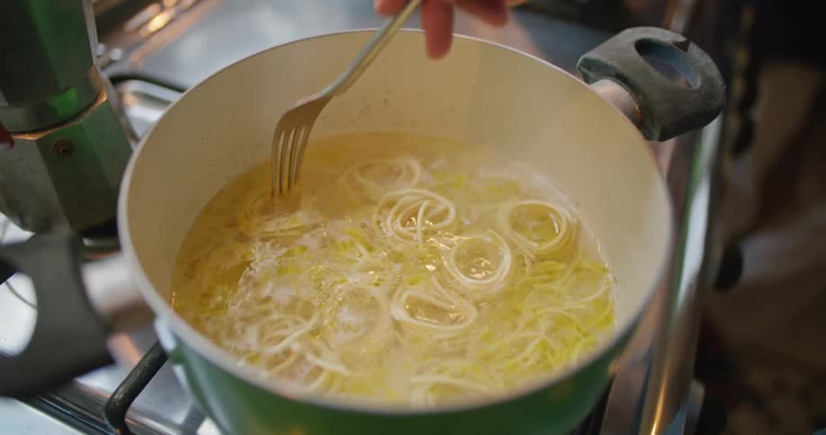 A person is cooking spaghetti in a pot
