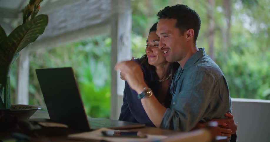 A man and woman hug and talk on the laptop