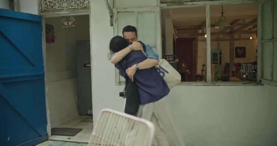 A woman enters the yard and hugs a man