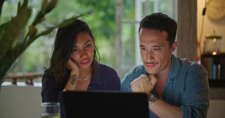A woman smiles as she and her date look at a computer screen and talk