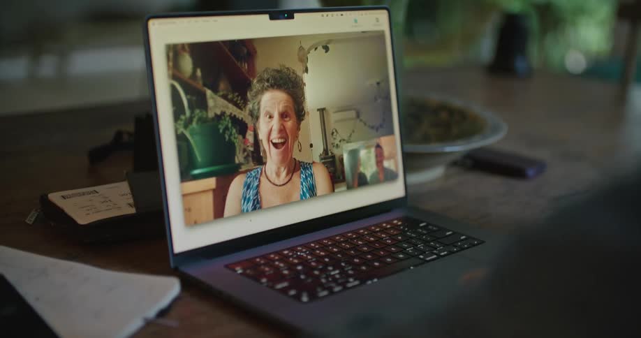 Happy mature woman laughs while talking on a video call on a laptop