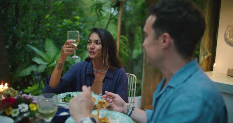 A woman holding a wine glass talks and smiles with her dinner date