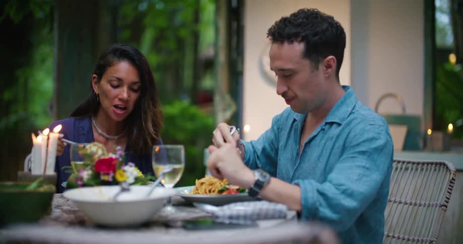 Young couple eating a hearty meal at candle light in a table in the backyard