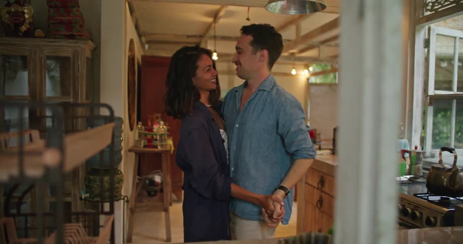 Young happy couple laugh and talk while dancing in the kitchen at home