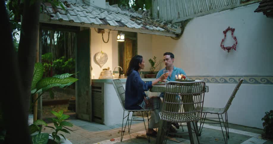 A man and a woman are sitting down at a table eating and talking
