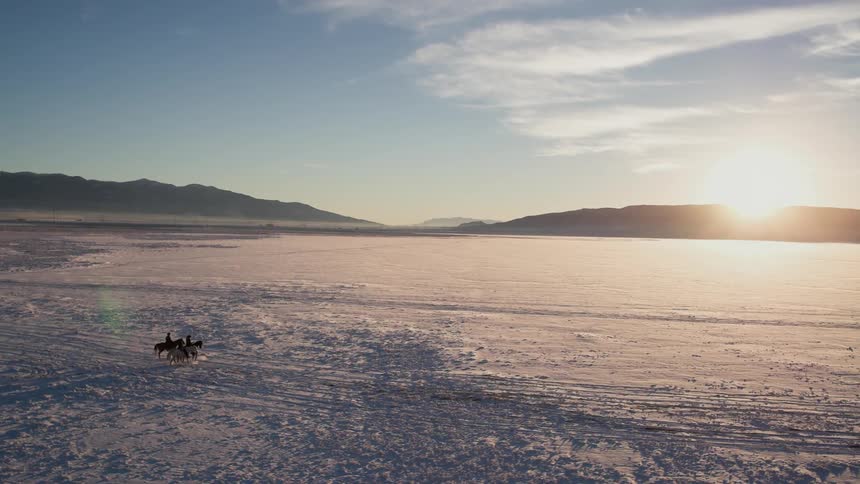 Men riding horses in slow motion in the snow